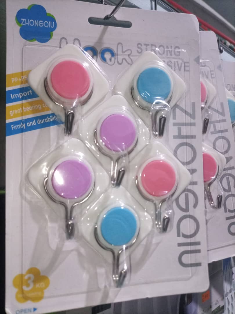 Détail d'un accroche mural adhésif Zhonghou collé sur un mur blanc, supportant un cadre